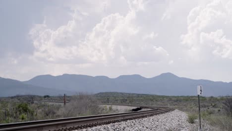 Vías-De-Tren-En-Primer-Plano-Y-Los-Interminables-Cielos-De-Texas-Que-Lo-Rodean,-Con-Montañas-Al-Fondo