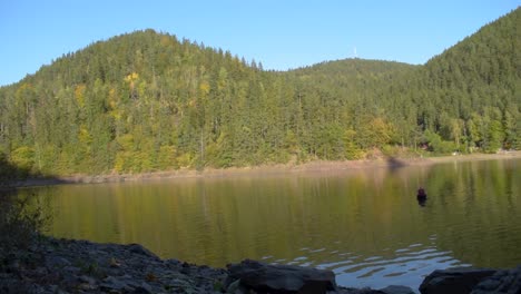 Scenic-view-of-a-big-lake-with-reflection-on-the-water-and-hills-in-the-background-in-autumn