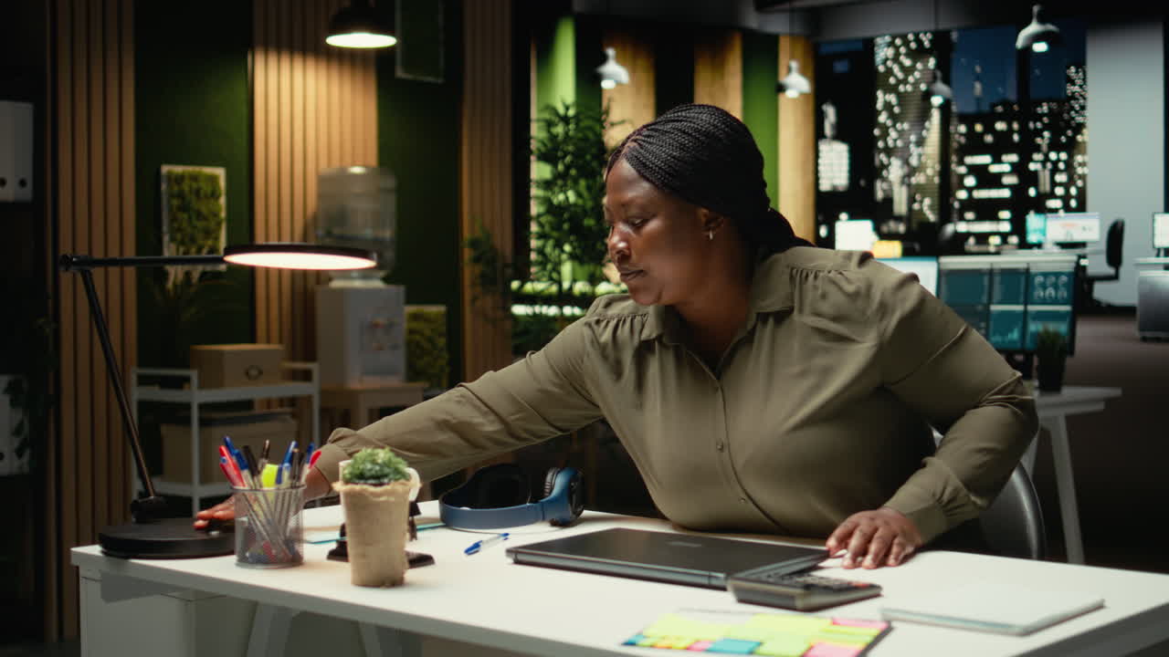 Black business manager closing her laptop after overtime late at night