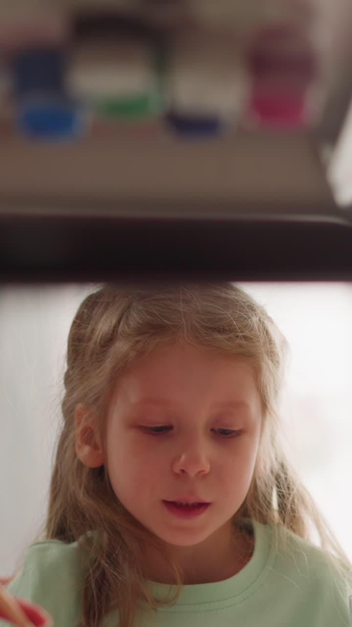 Adorable little girl looks at sister dripping paint into water making Ebru design at home closeup slow motion. Art development for small students