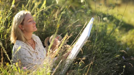 an artist paints a picture on a sunny summer day in a meadow - an artist paints a picture on a sunny summer day in a meadow. artist girl draws nature