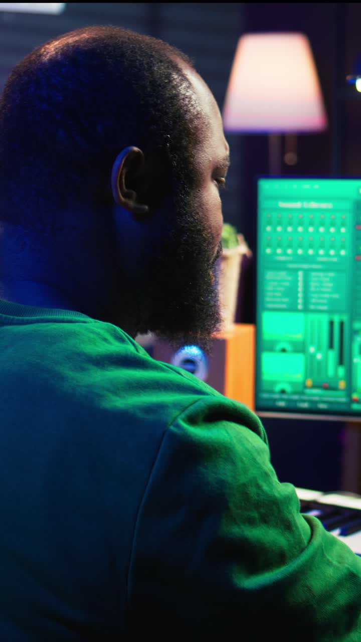 Afro-Amerikaanse man maakt muziek in thuisstudio met neonverlichting