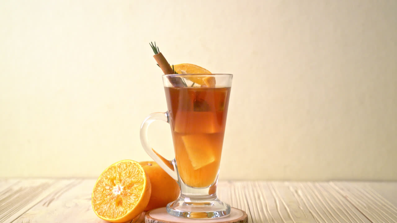 Un bicchiere di caffè nero americano ghiacciato e uno strato di succo di arancia e limone decorato con rosmarino e cannella