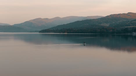 peaceful paddleboarding at sunset on a calm lake with mountains in the background