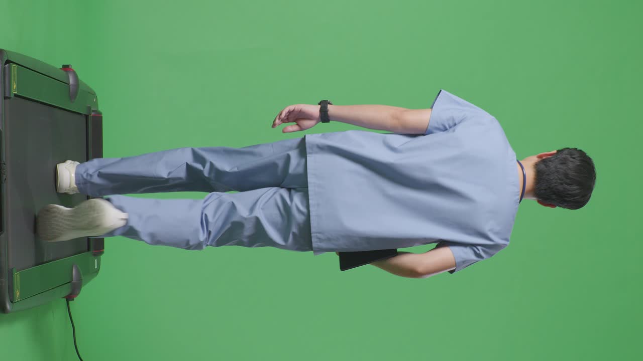 병원에서 녹색 화면 배경에서 걸어가는 동안 태블릿을 들고 있는 스테토스코프를 가진 아시아 남성 의사