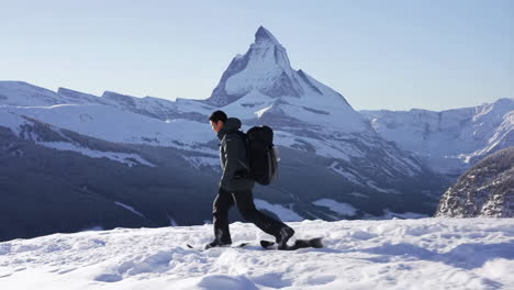 a person snowshoeing in a snowy mountain landscape with a prominent peak in the background