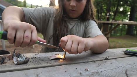 niño produciendo chispas de un encendedor de magnesio con un cuchillo
