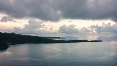 scenic view of gray stormy clouds over the calm ocean at the naviti island in fiji - slow tilt down shot