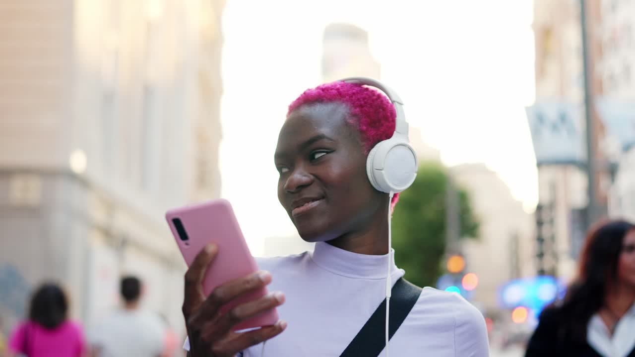 Young woman with pink hair enjoying music with headphones in the city