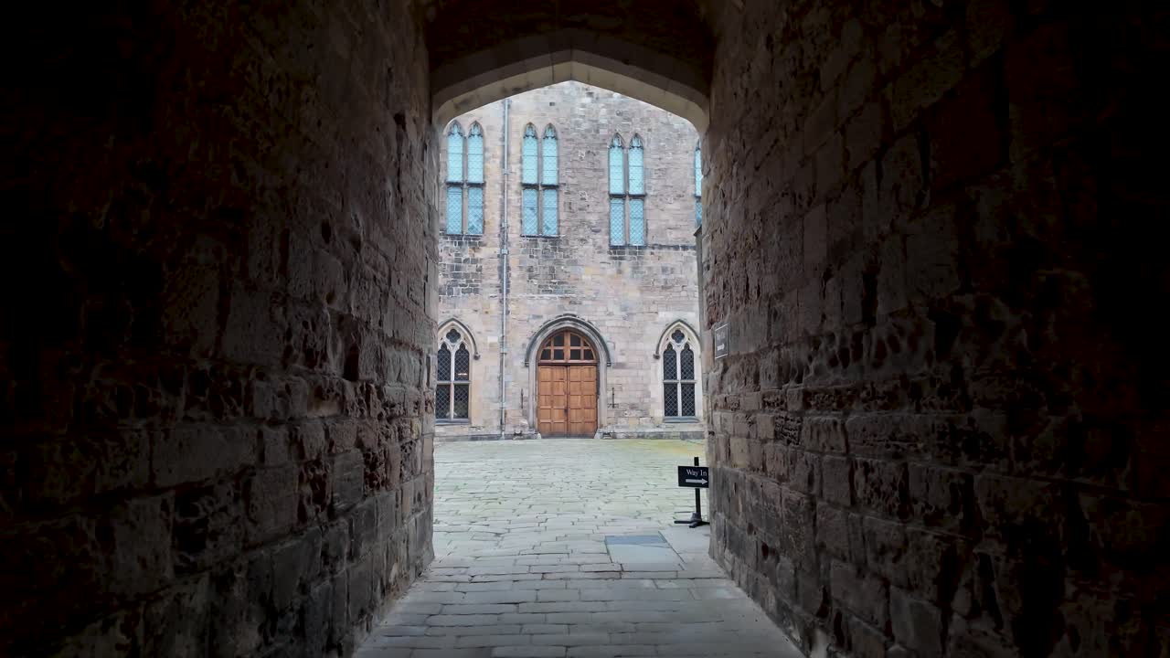 A dark passage leads to a sunlit castle courtyard, framed by archways and stone walls