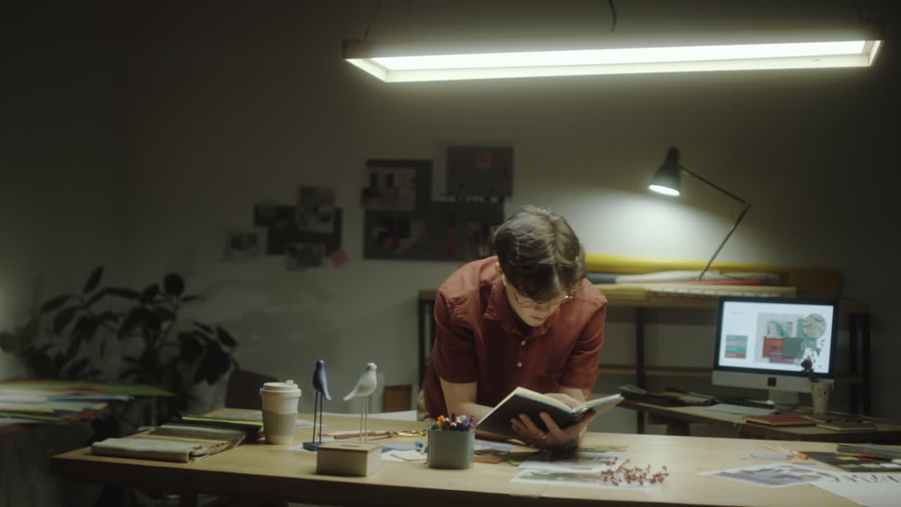 Young man working on a creative project at his desk in a dimly lit home office