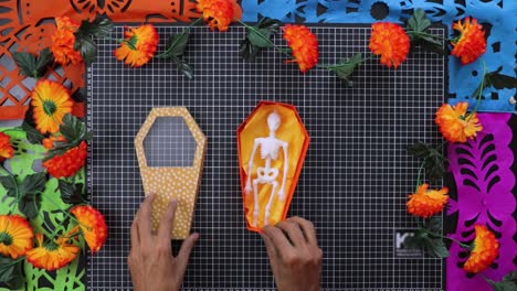crafting coffin cardboard box with skeleton and marigolds for day of the dead, top down view