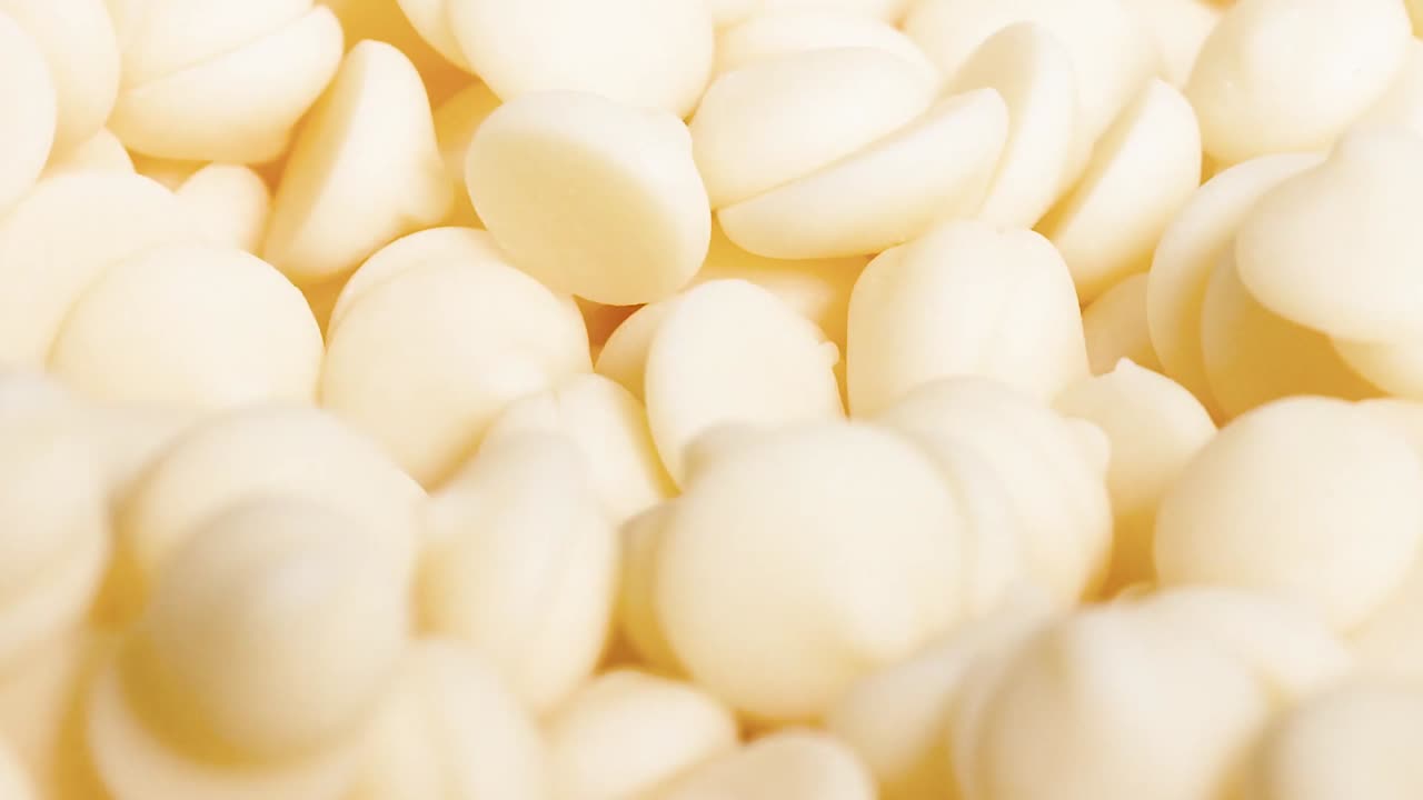 Detailed view of white chocolate chips being scooped with a spoon, highlighting their smooth texture.