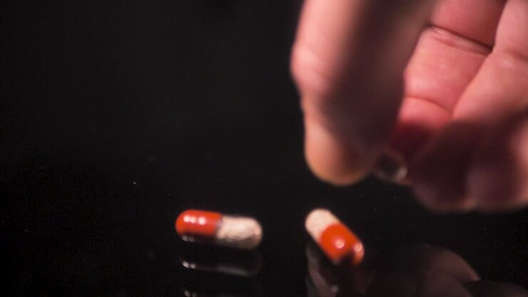 The man picks up pills from the table, enzyme, pancreatic treatment