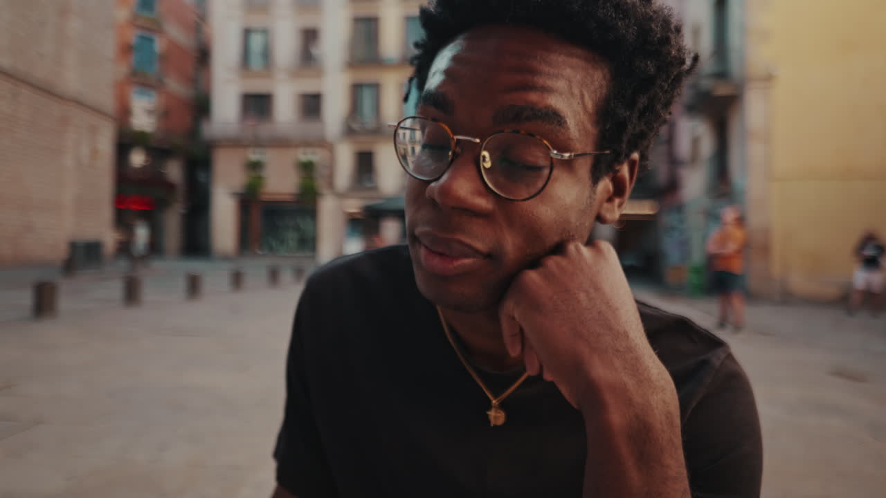 Young Black Man with Glasses Drinking Beverage in City Square