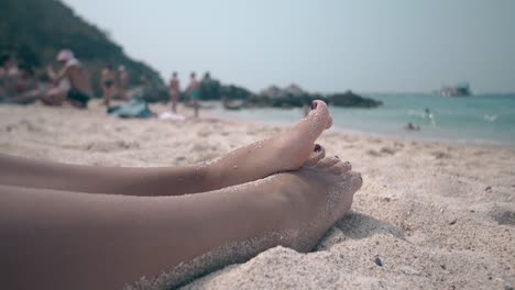 girl with red pedicure shakes sand and tiny stones off feet