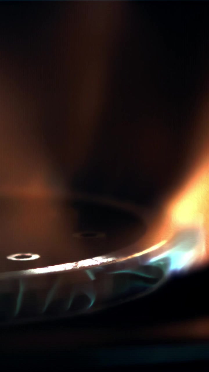 Close-up of a Gas Stove Burner Igniting with Blue and Orange Flames