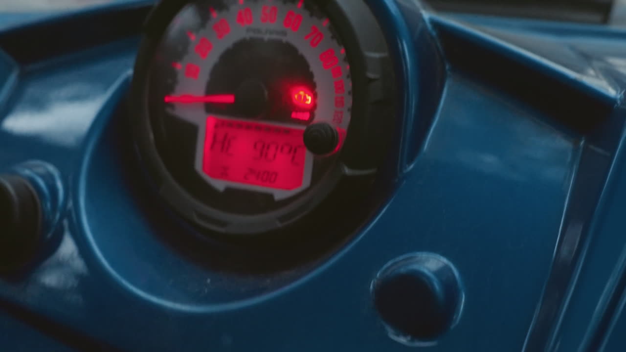 ATV dashboard display. Closeup view of blue vehicle dashboard with illuminated readouts. Detailed image showing redlit digital speedometer and control switches on glossy plastic surface