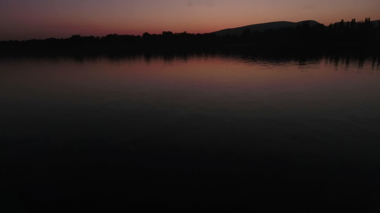 일몰 또는 일출을 드러내며 물 위로 모션 샷을 기울입니다.