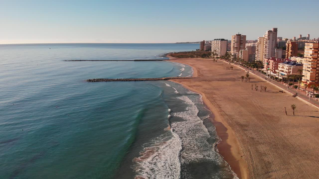 Onde lente e calme che si infrangono su una spiaggia spagnola deserta, El Campello, Costa Blanca
