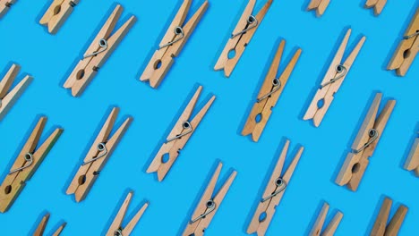 clothespins-laid-out-in-pattern-opening-and-closing-stop-motion-effect-on-vibrant-blue-background