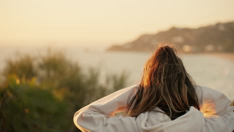 Zeitlupenaufnahme-Einer-Frau,-Die-Mit-Den-Haaren-Wedelt,-Während-Sie-Den-Sonnenuntergang-über-Dem-Meer-Beobachtet