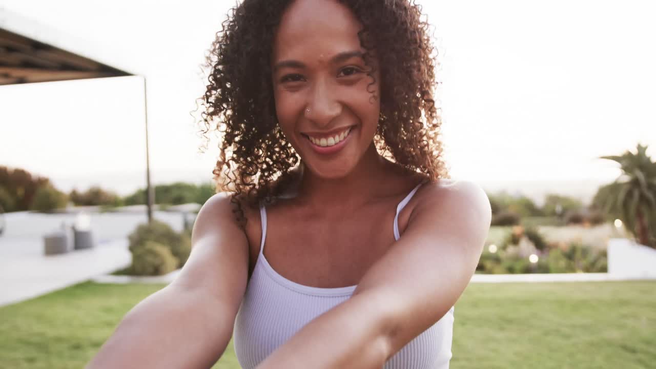 retrato de una feliz mujer biracial sosteniendo la mano de su pareja y sonriendo en el jardín en cámara lenta