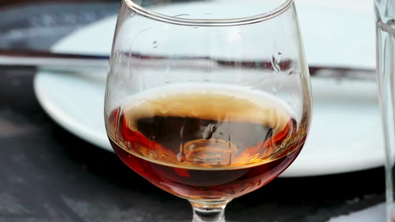 vaso de bebida espirituosa griega metaxa de cerca mientras la gente está cenando