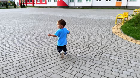 following a beautiful toddler running outdoors. smiling active caucasian kid having fun on the walk in summer.