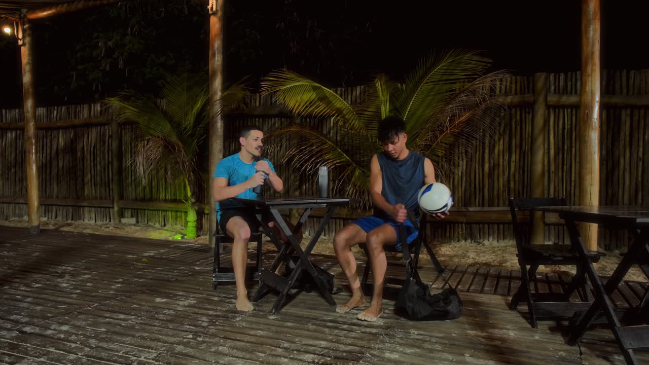 Two men socializing at a dimly lit outdoor patio at night
