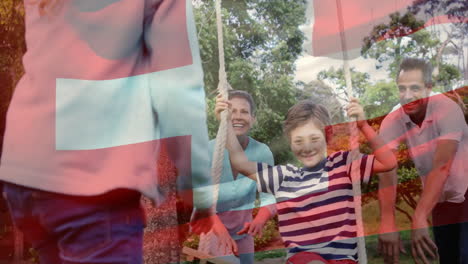 animation of flag of switzerland over caucasian family playing in garden