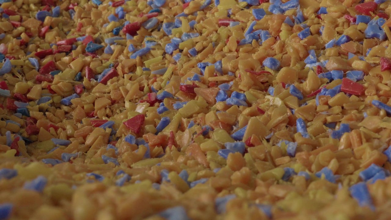 Dense pile of colorful shredded plastic flakes in yellow blue and red at recycling facility