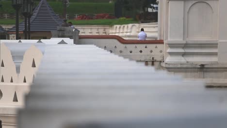 Close-up-view-from-top-of-the-wall-of-the-Temple-of-the-Sacred-Tooth-Relic-or-Sri-Dalada-Maligawa-with-tourists-watching-and-walking-around-in-Sri-Lanka,-Dec