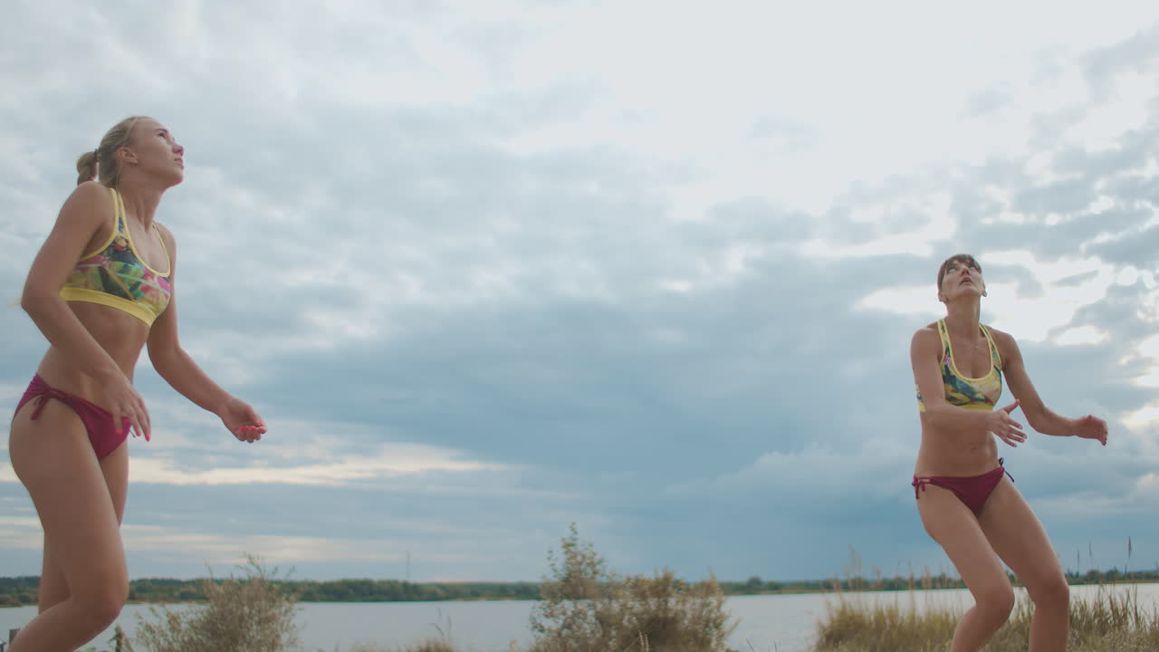 las jóvenes deportistas están entrenando en la cancha de voleibol de playa saltando y jugando a la pelota preparándose para la competencia