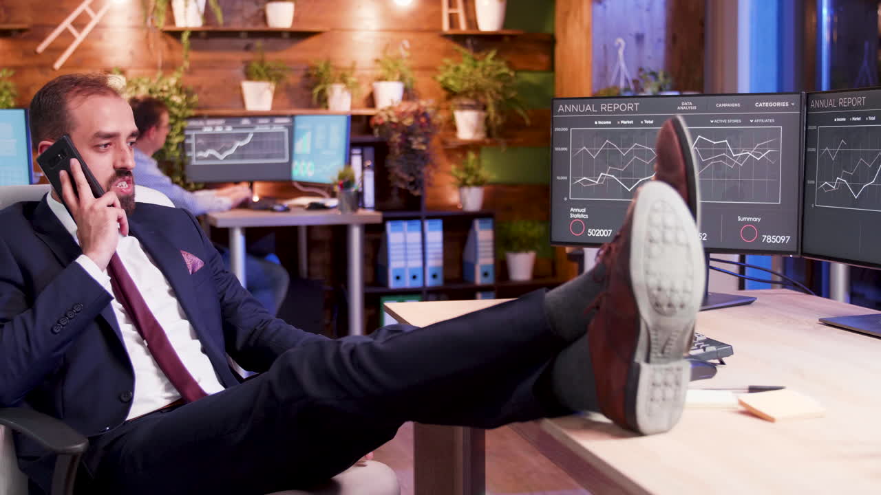 Businessman Relaxing at His Desk While Talking on the Phone