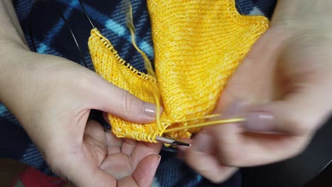 women's hands knit woolen jacket with knitting needles. top view, close-up of hands and knitting.