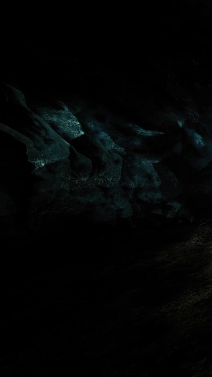 Exploring a dark cave with unique rock formations and dim light