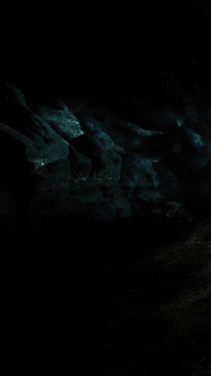 Exploring a dark cave with unique rock formations and dim light