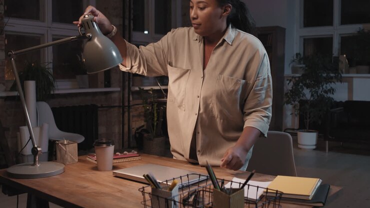 Woman preparing to work on her laptop at a desk in a dimly lit office