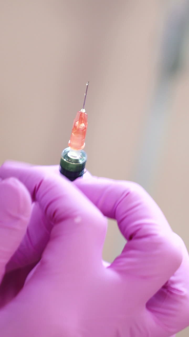 Close up of cosmetician s hand preparing a syringe for injection. Blur. Handheld real time close up shot Vertical video