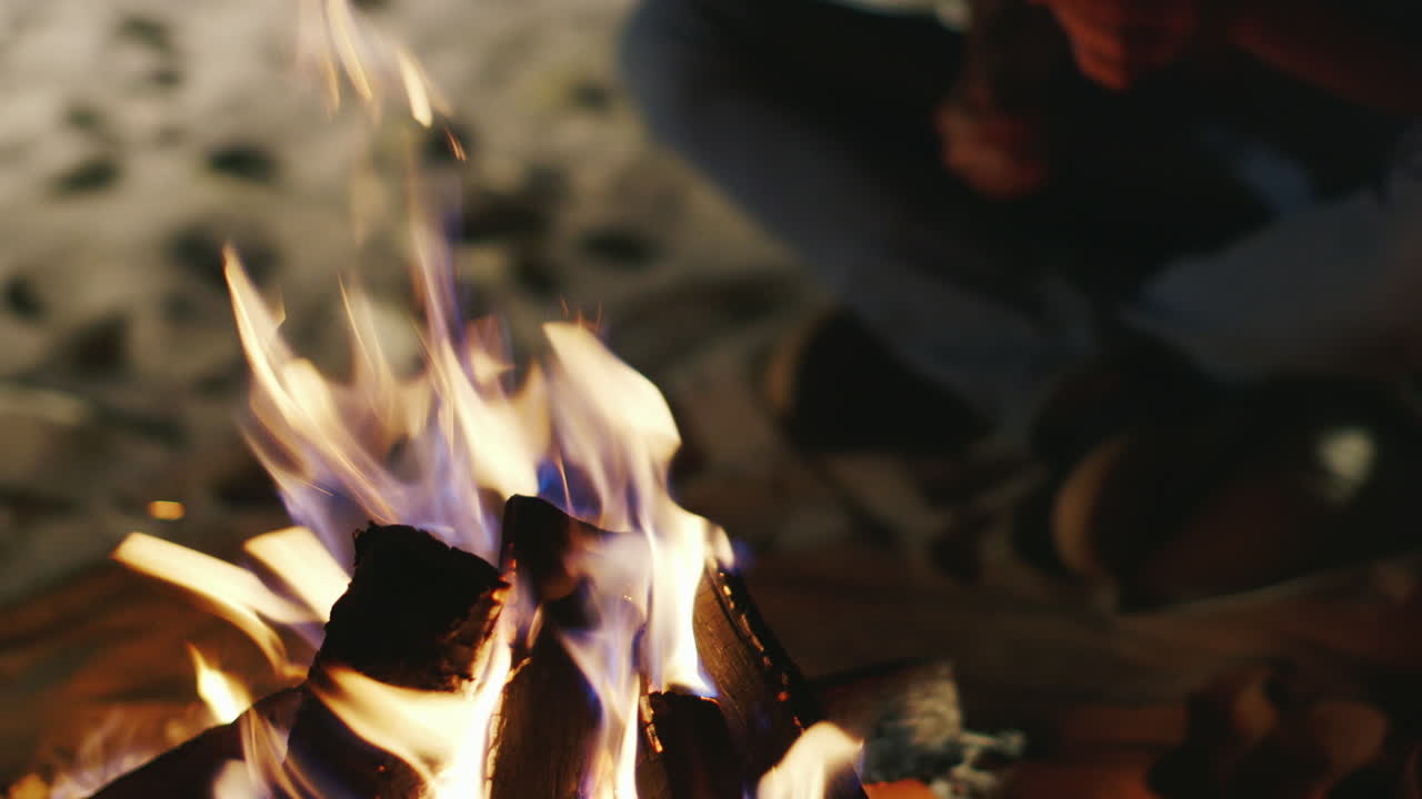 manos sosteniendo un palo con un malvavisco sobre el fuego