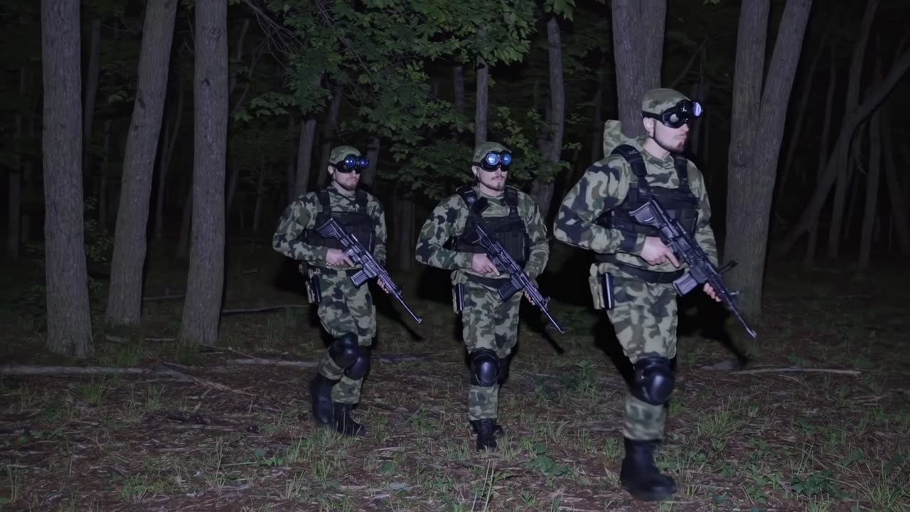 Night vision video scene of soldiers in camouflage patrolling a forest