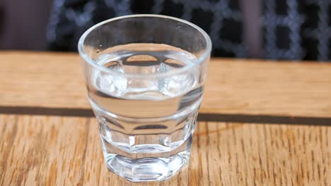 pouring water into a glass on a wooden table