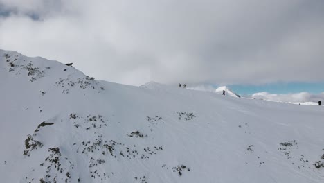 Flyover-Slowmotion-drone-shot,-flying-past-a-couple-of-skiers,-revealing-the-Vihren-mountainpeak-in-Pirin,-Bulgaria