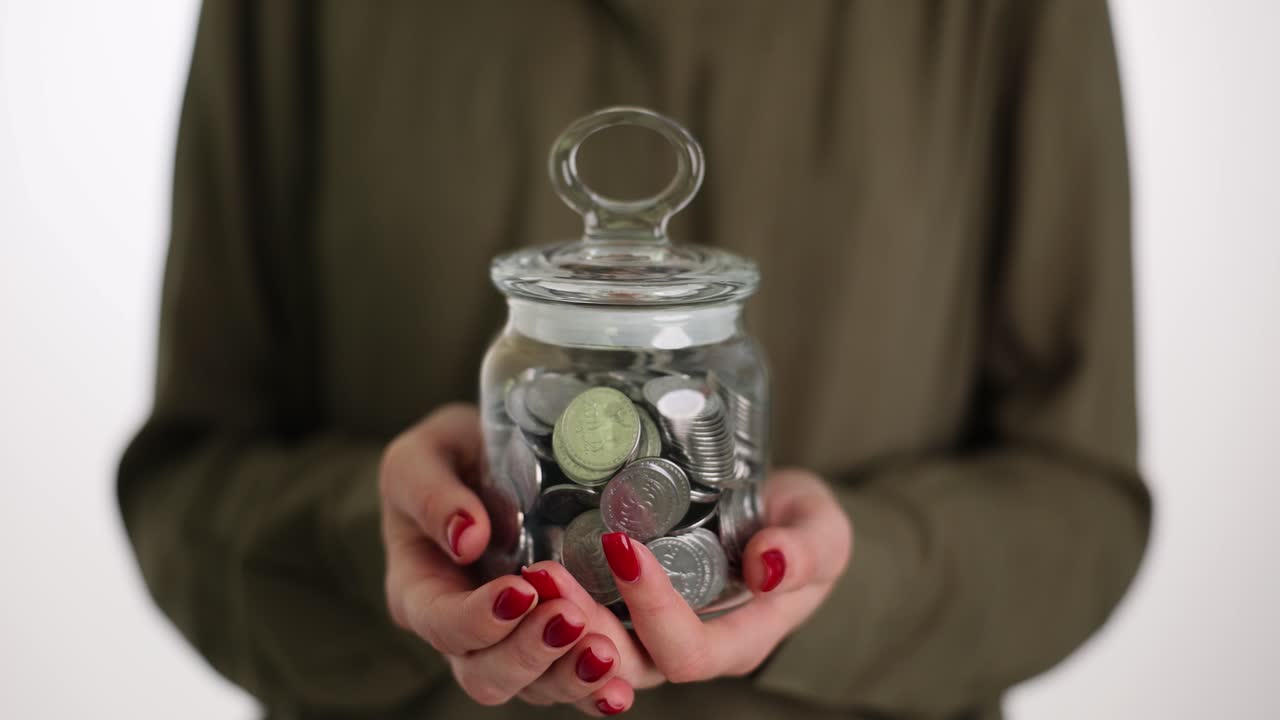 Hands holding a jar full of coins