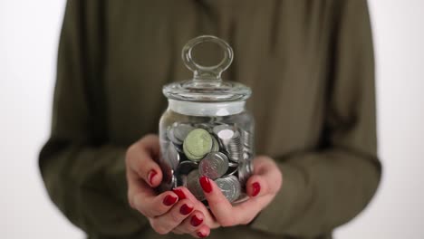 Hands holding a jar full of coins