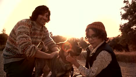 father and son hikers petting and kissing dog in nature