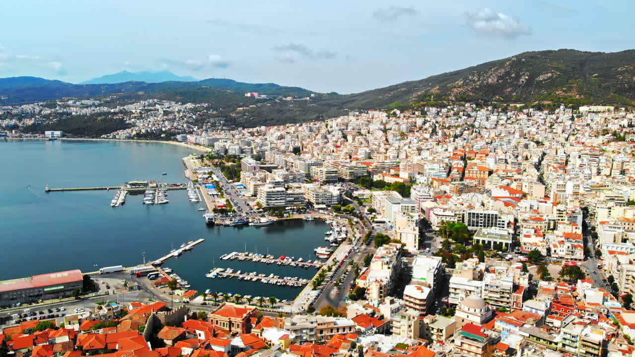 Aerial view of Kavala, a lot of buildings, Aegean sea coast, sea port, green hills in the distance, Greece