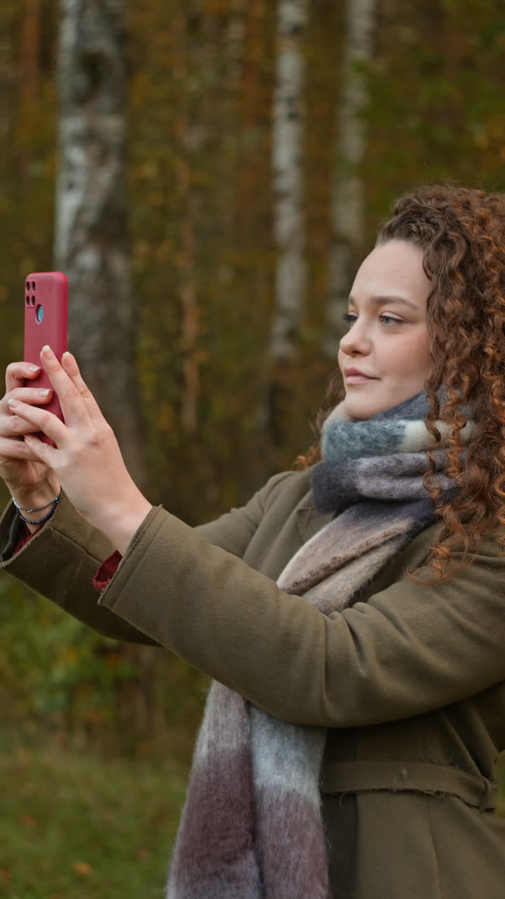 Woman taking photo with phone in autumn forest