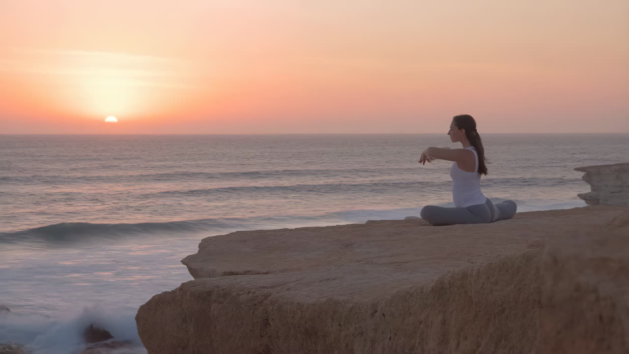 mujer meditando en un acantilado con vistas al océano al atardecer